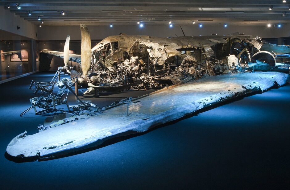 Vraket efter ett st&ouml;rtat flygplan, effektfullt upplyst i en utst&auml;llningslokal.