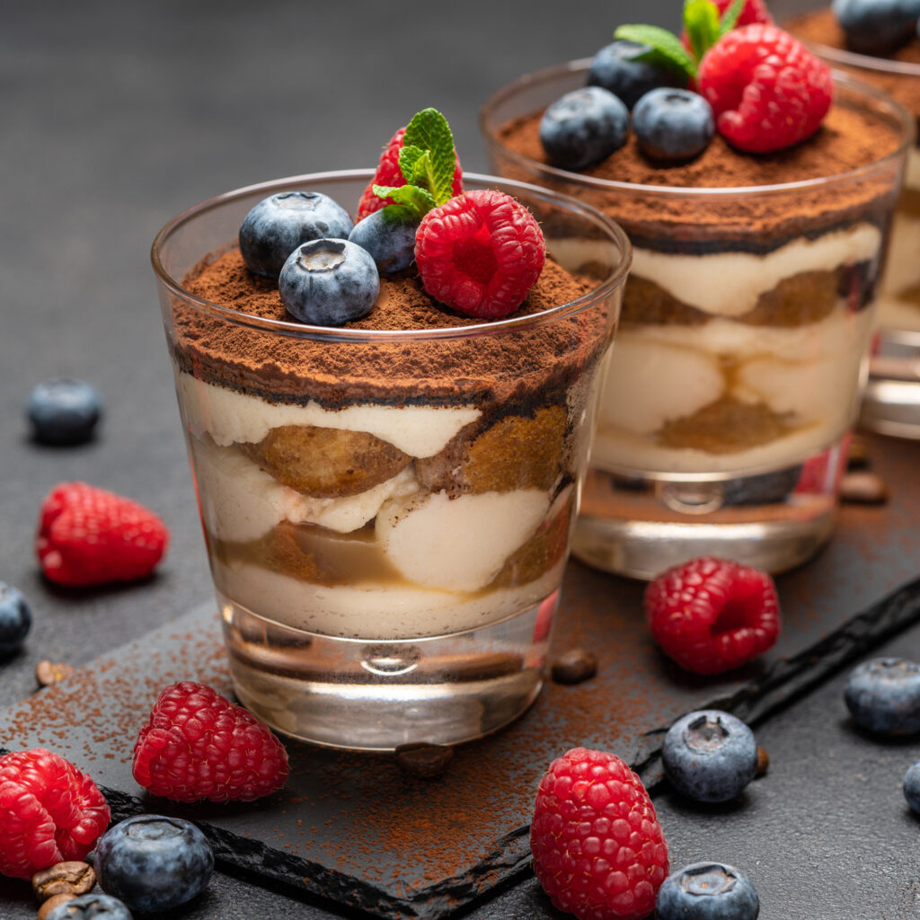 Dessert i glass liknande Tiramisu toppade med blåbär och hallon.