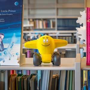 Seriefiguren Barbazoo i formen av ett flygplan ståendes i en bokhylla i museets bibliotek
