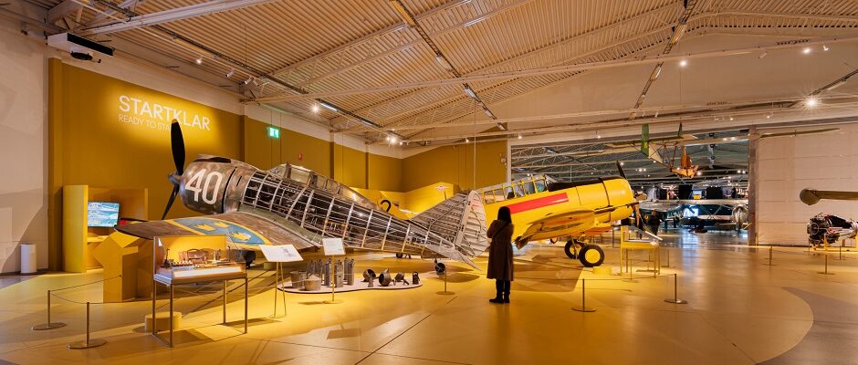 En bes&ouml;kare st&aring;r framf&ouml;r ett &auml;ldre flygplan i en av utst&auml;llningshallarna.