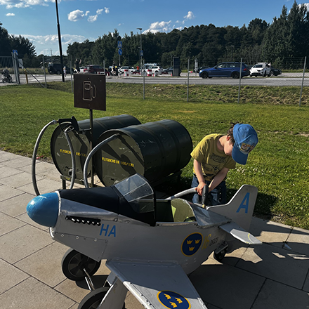 Ett barn tankar ett leksaksflygplan p&aring; lekplatsen utanf&ouml;r Flygvapenmuseum.